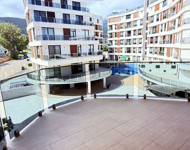 Geniş terastan ortak havuz ve apartman blokları görünüyor