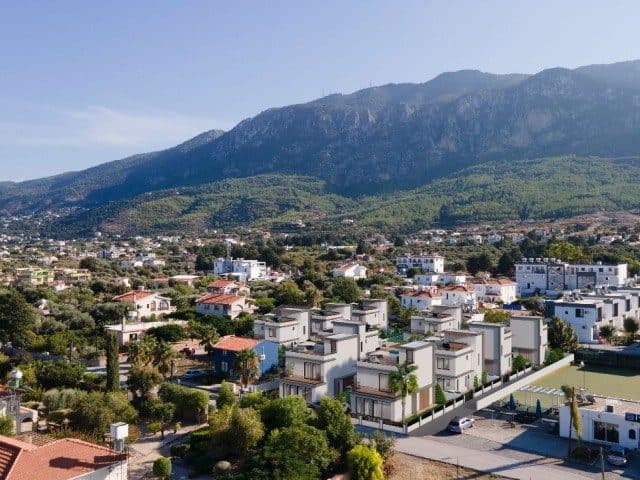 Villalar önünde yeşil alanlar, arkada dağ silsilesi görülüyor