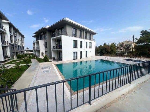 Apartman blokları, çevrili havuz ve balkonlar görünüyor