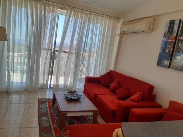 Kırmızı koltuklar, ahşap sehpa ve sürgülü balkon kapısı