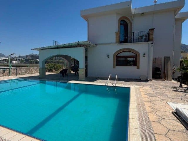 Öndeki havuz, taş döşeli alan ve üst kattaki balkon
