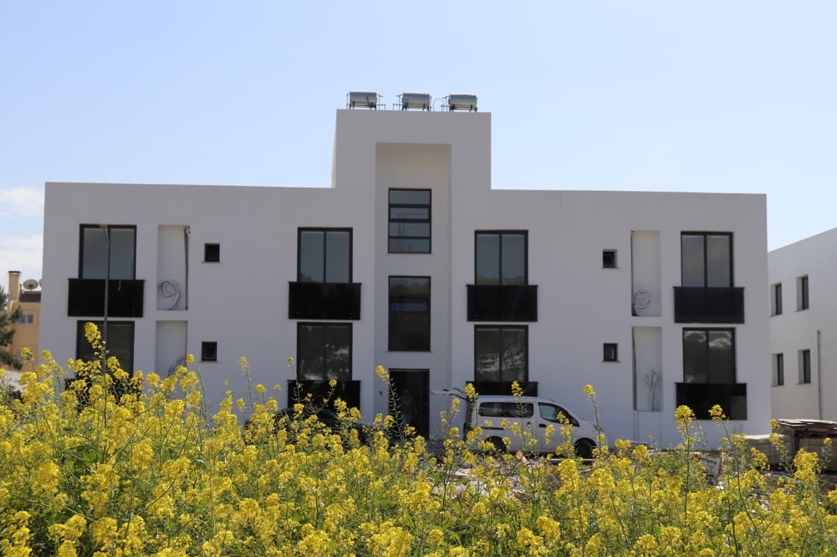 Front facade of a modern designed building with a flowery garden.