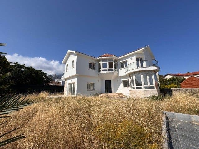 Beyaz cepheli villa, kuru otlarla kaplı geniş bahçeden görülüyor