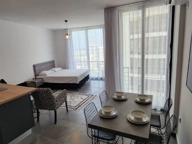 Yatak, yemek masası ve geniş camlı balkon aynı karede