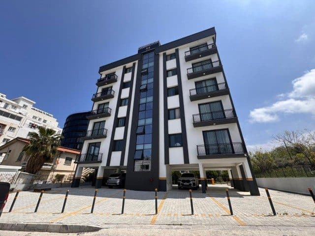 Apartmanın geniş açıdan görünümü ve önündeki açık park alanı
