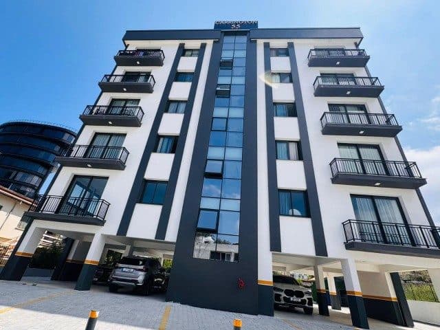 Siyah detaylı apartman cephesi ve zemin kattaki araç park alanı