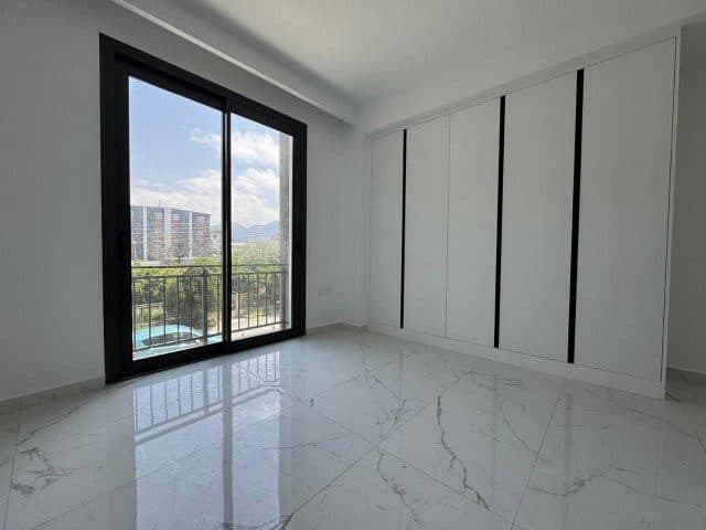 Boş yatak odasında gömme dolap ve dağ manzaralı balkon kapısı