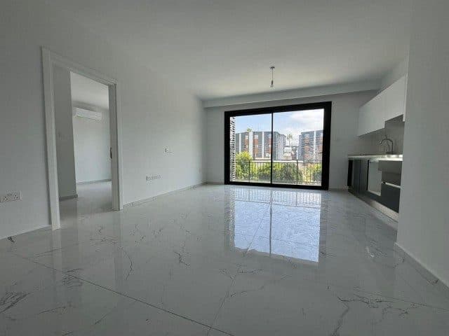 Boş salonun karşısındaki ankastre mutfak ve geniş camlı balkon kapısı