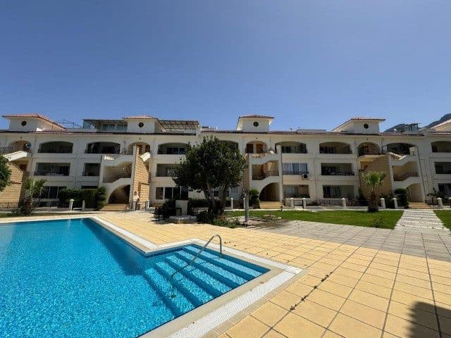 Havuz önünde açık renkli apartman ve taş döşeli alan