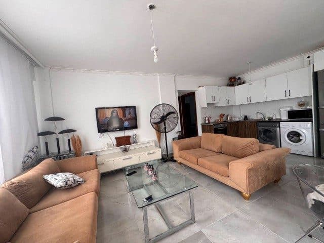 Cam sehpa ve kahverengi koltuklar açık mutfakla aynı alanda.