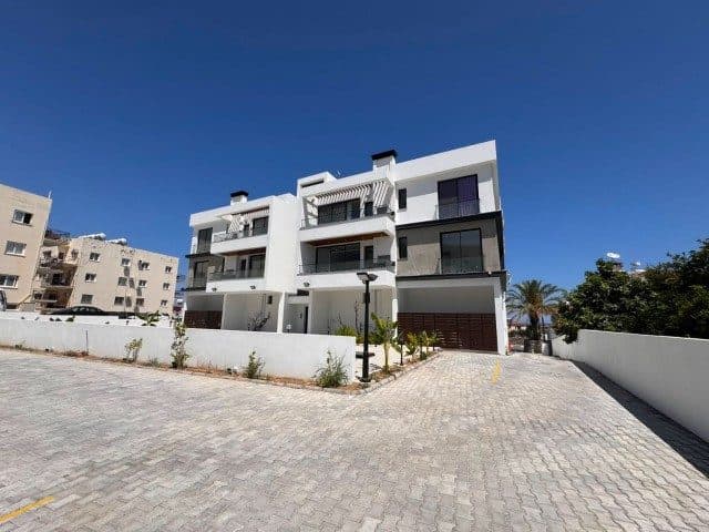 Açık renkli apartman cephesi ve geniş döşeli araç alanı