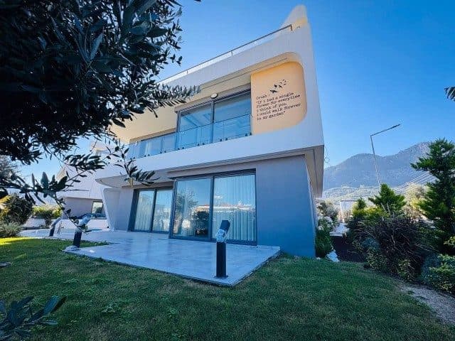 Cam balkonlu modern cephe, çim bahçe ve arkada dağlar