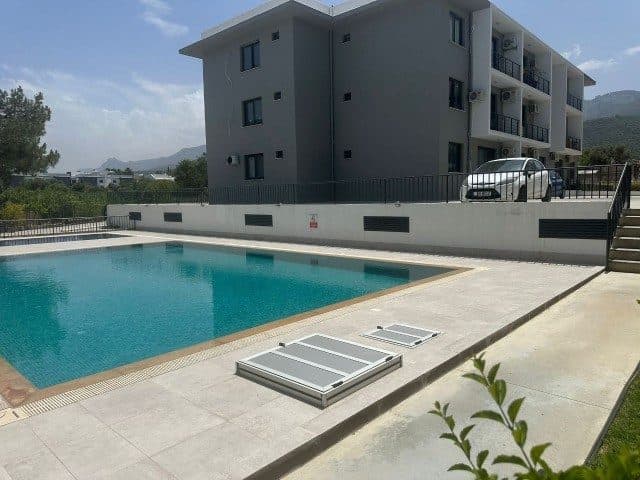 Apartman bloğu, havuz terası ve giriş yanındaki park alanı