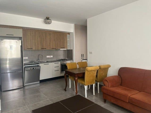 Ahşap dolaplı mutfak, yemek masası ve turuncu koltuk
