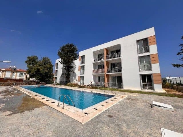 Dikdörtgen havuz, açık renkli apartman ve balkonlar