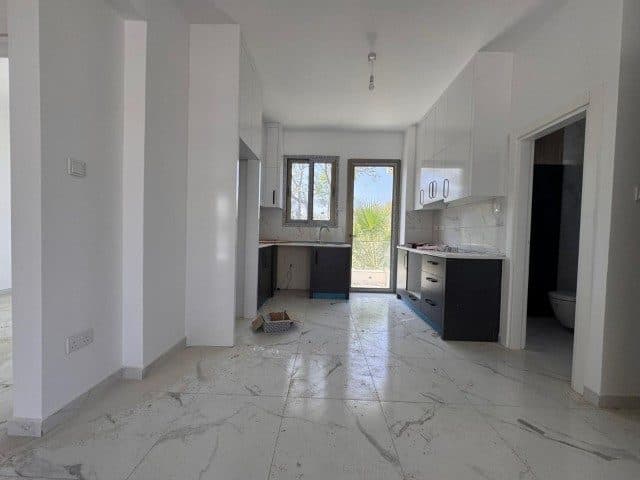 Mermer desenli zeminin yanında koyu renkli alt dolaplı mutfak