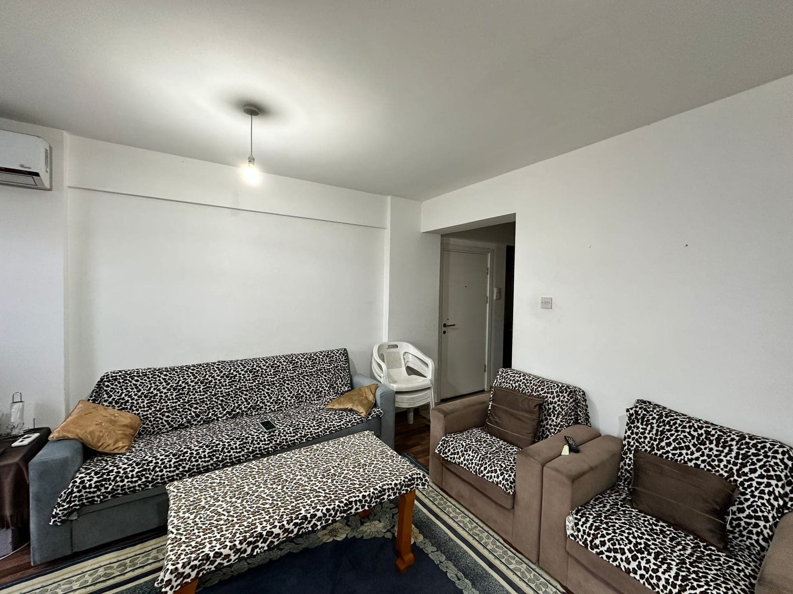 Living room with leopard print sofa set and air conditioner on the wall.