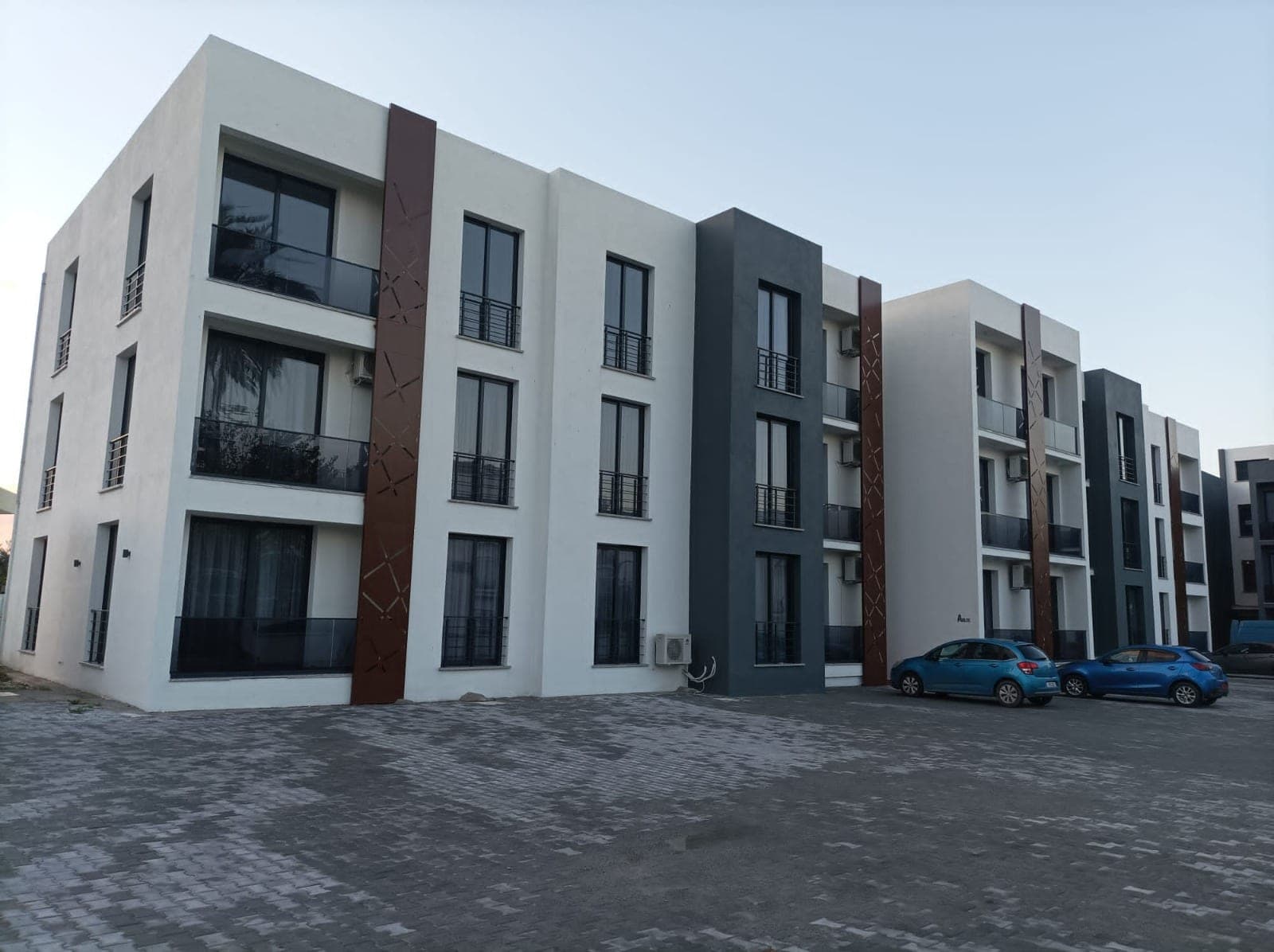 Modern tasarımlı apartman binası ve önündeki otopark alanı