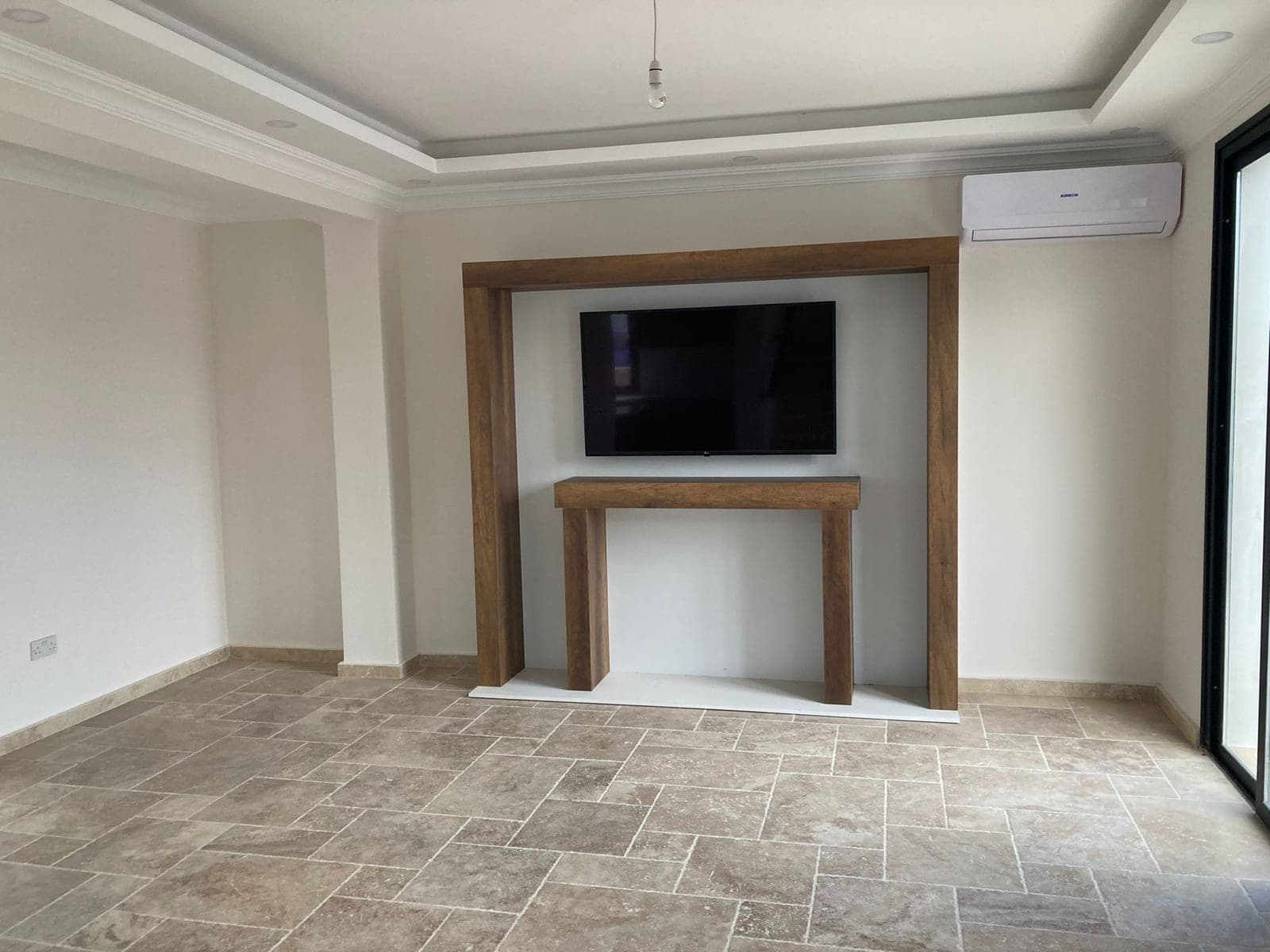 Empty living room with wall-mounted TV and air conditioning unit