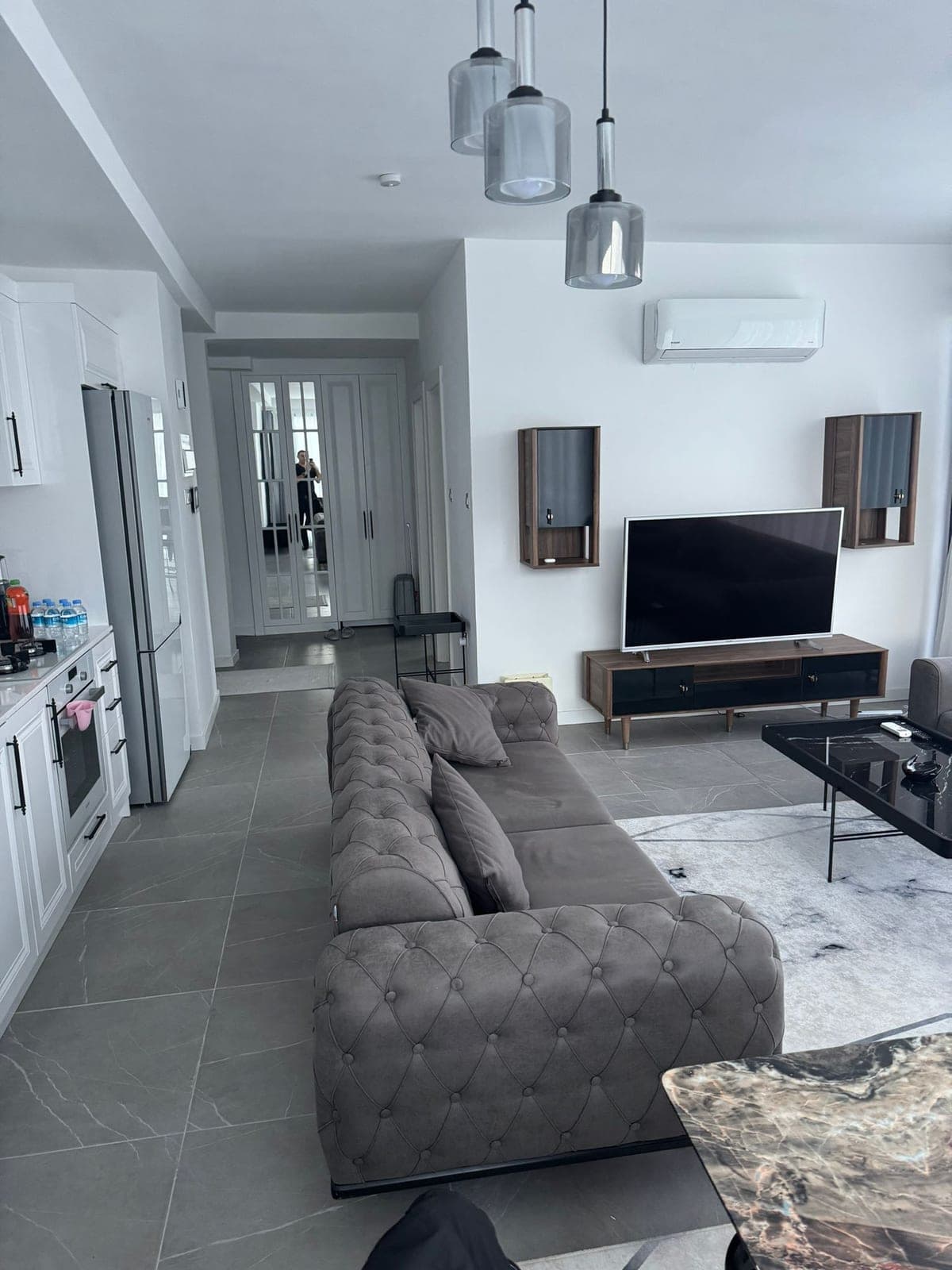 Açık plan salon ve mutfak, gri koltuk takımı ve TV ünitesi.