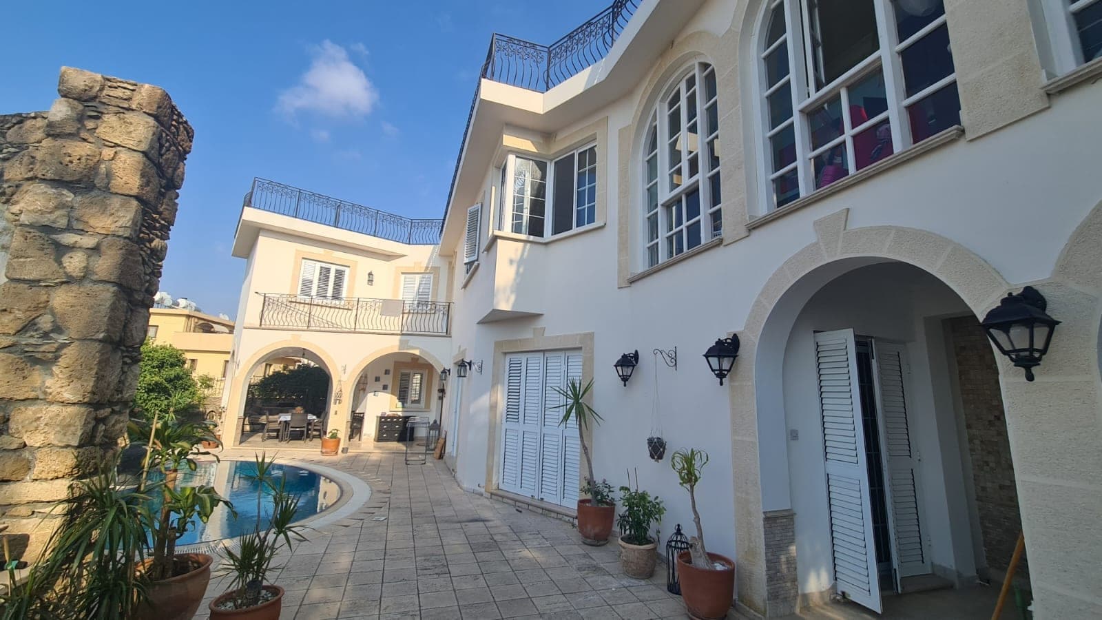 Beyaz cepheli villa, havuz ve taş duvar detayları