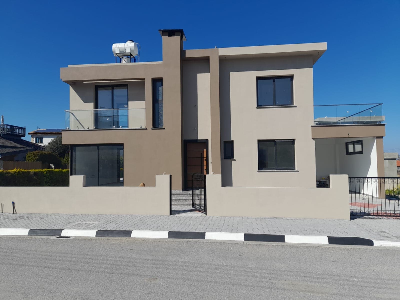 Exterior of a modern detached villa with garden and balconies.