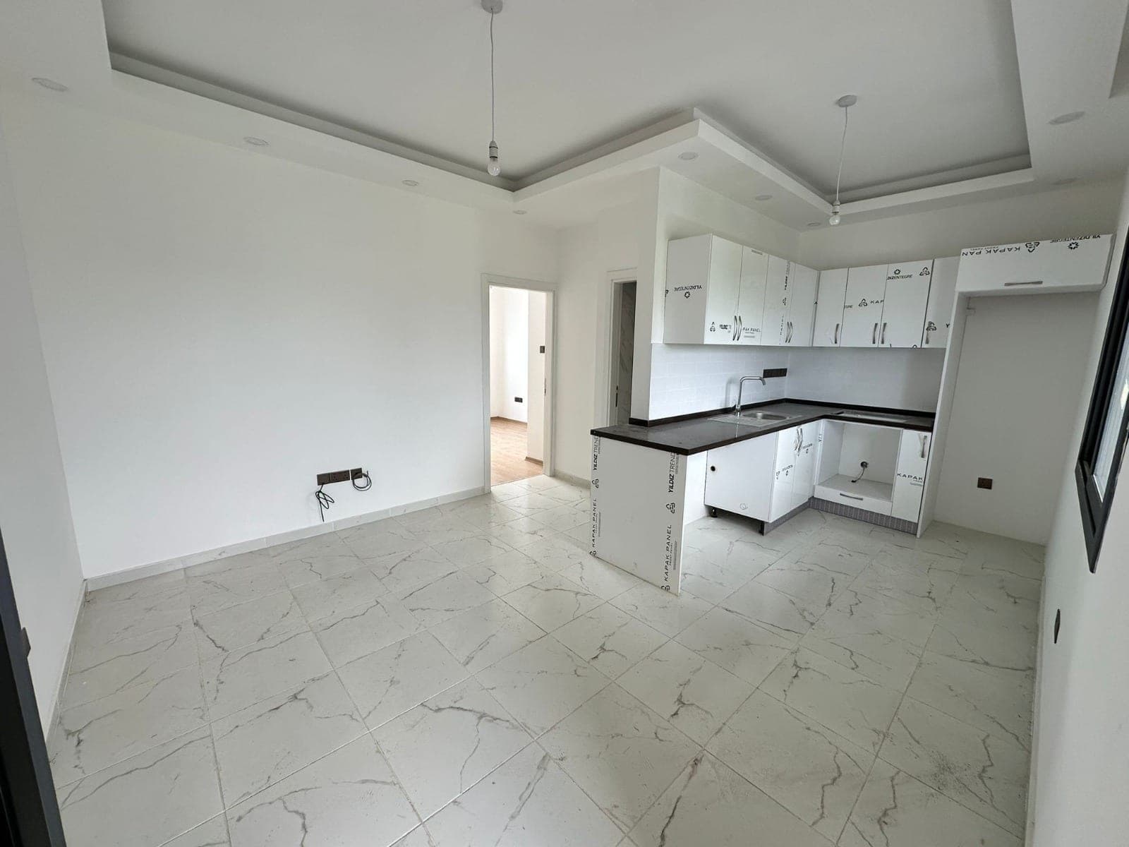 Open-plan living room and built-in kitchen area with white cabinets.