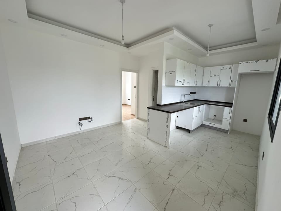 Açık plan salon ve ankastre mutfak alanı, beyaz dolaplar.