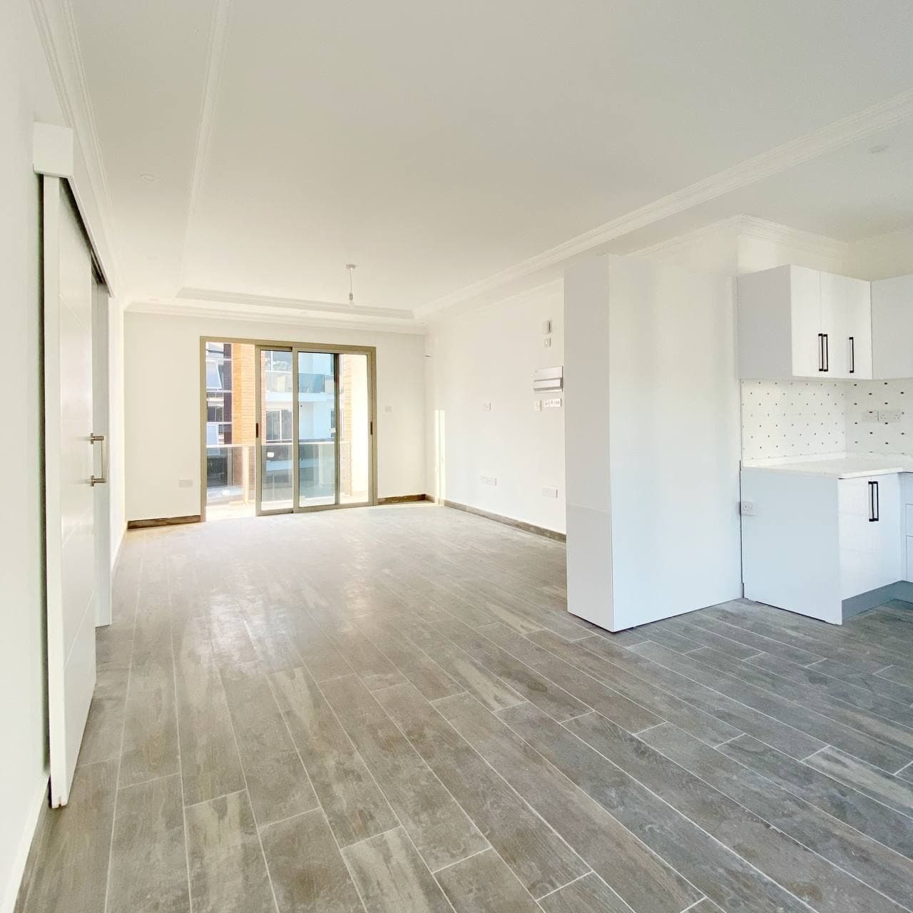 Open-plan living room and kitchen area, sliding balcony door.