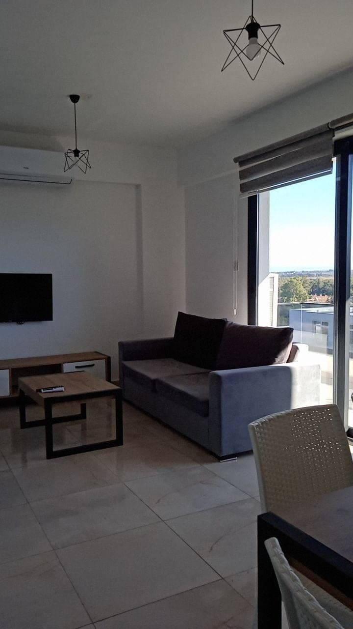 Living room with modern lighting, balcony, and distant building views.
