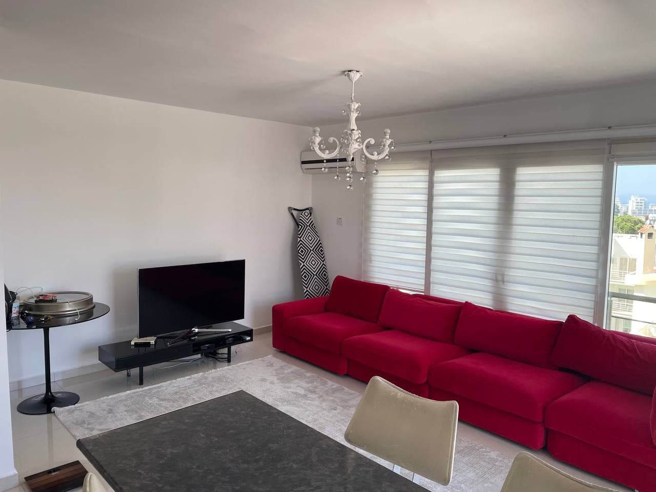 Spacious living room with red sofa, television, and dining table.