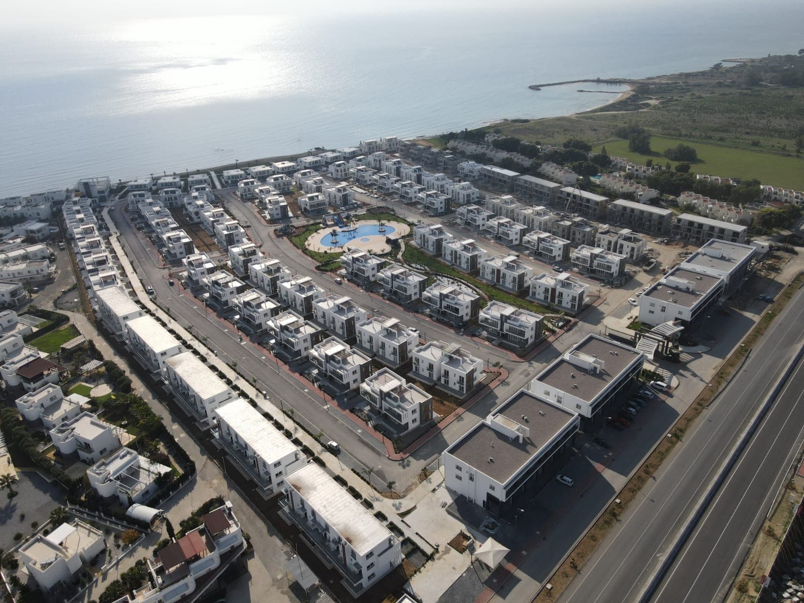 Deniz kenarında, ortak havuzlu ve otoparklı siteye kuşbakışı genel görünüm.