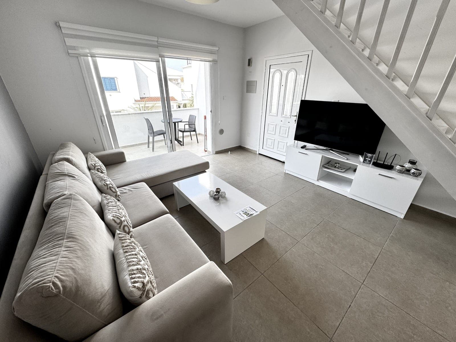 Living room with L-shaped sofa, TV unit, and sliding door to balcony.
