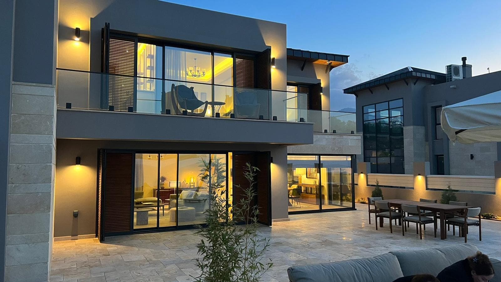 Modern villa exterior with evening lighting and pool area