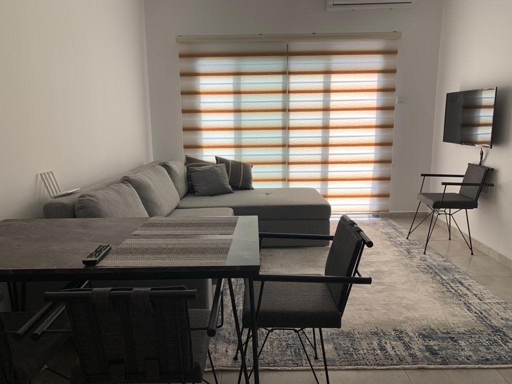Living room with grey sectional sofa, dining table, and wall-mounted TV.
