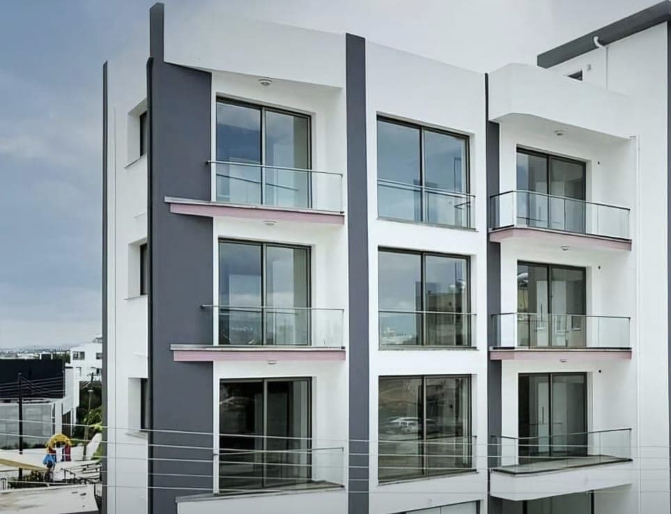 Exterior of a modern, multi-story apartment building with glass balconies.