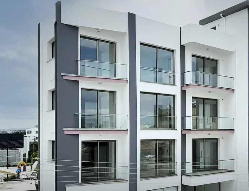 Modern tasarımlı, çok katlı apartman binasının dış cephesi ve cam balkonları.
