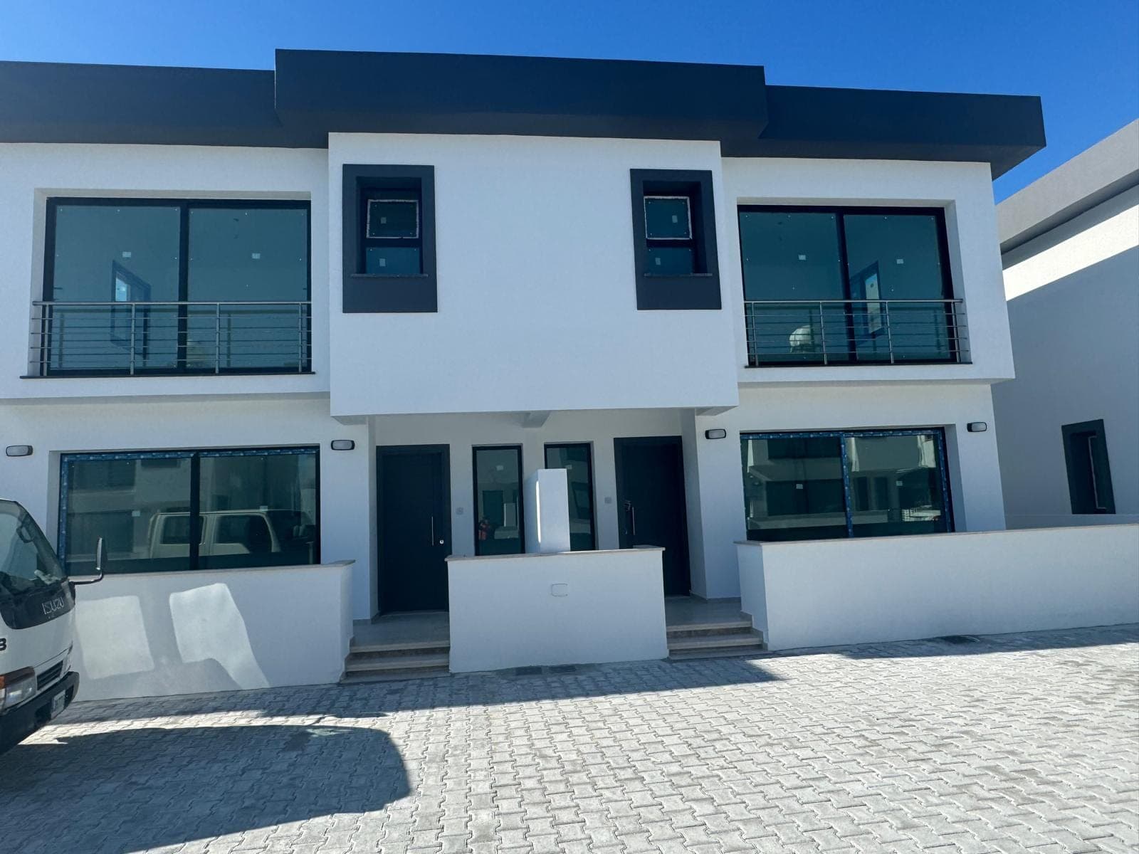 Modern designed, white-fronted semi-detached villa exterior and parking area.
