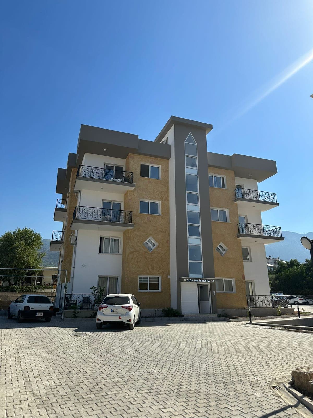 Exterior of a modern apartment building with parking area.