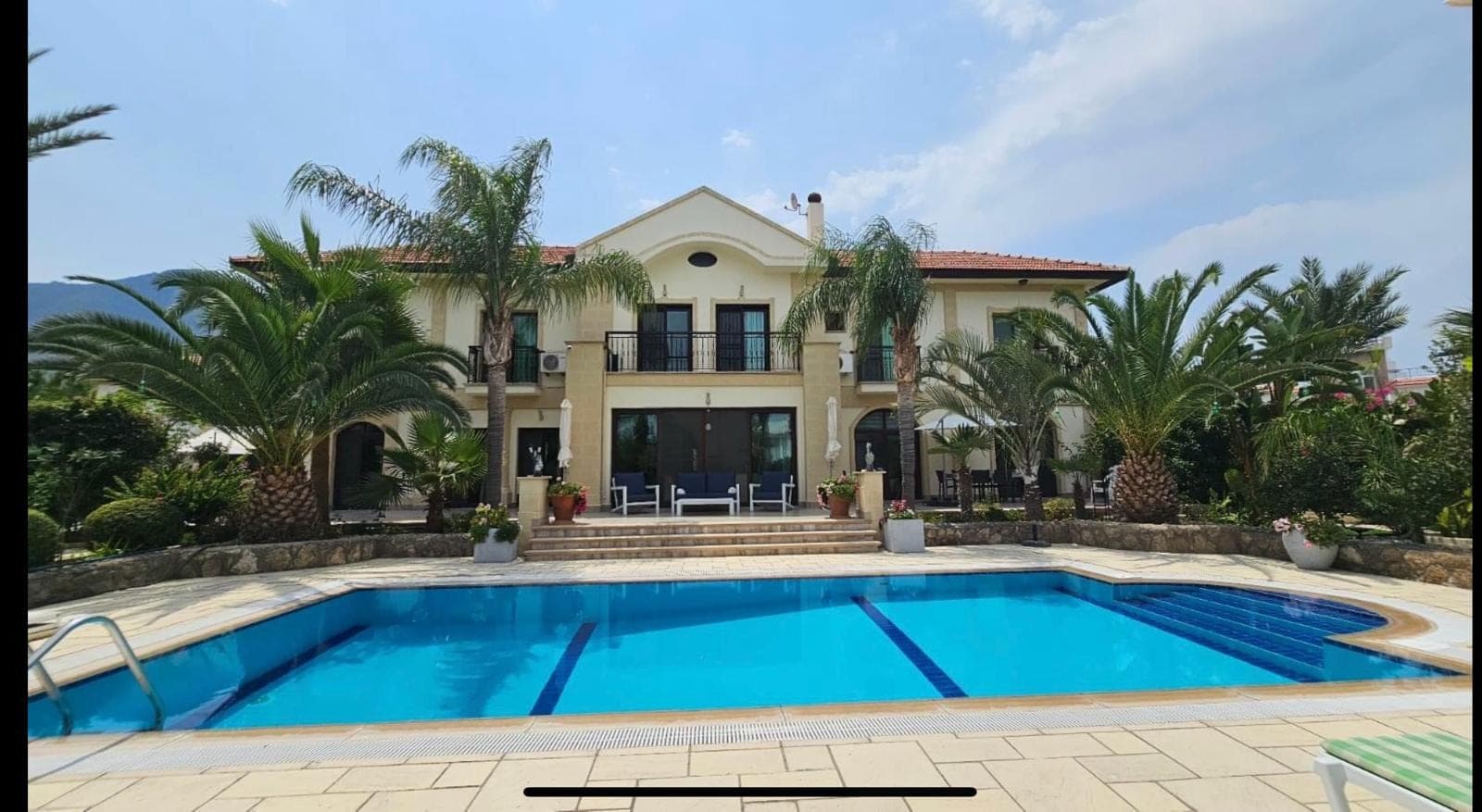 Villa exterior with large pool and palm trees