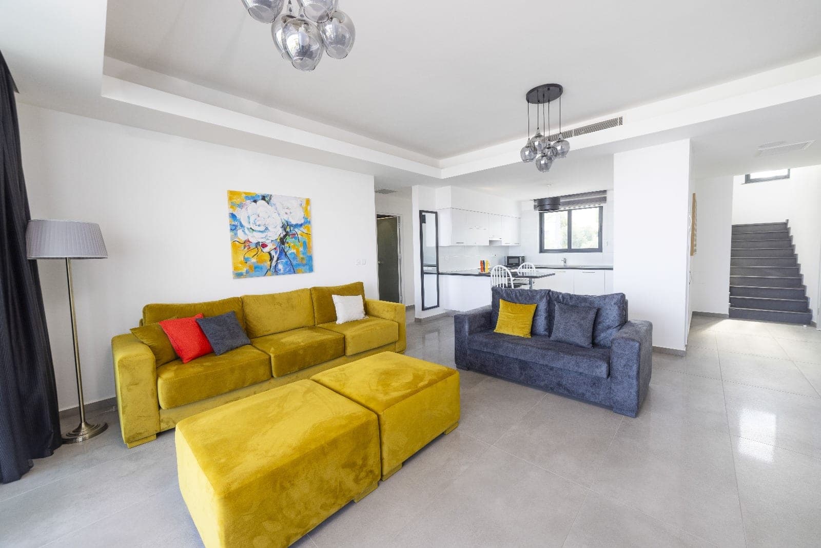 Open-plan living room and kitchen area with yellow and grey sofas.