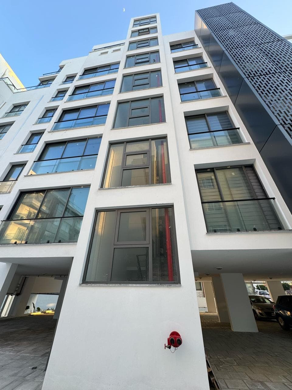 Parking area on the ground floor and balconies on upper floors of a modern building