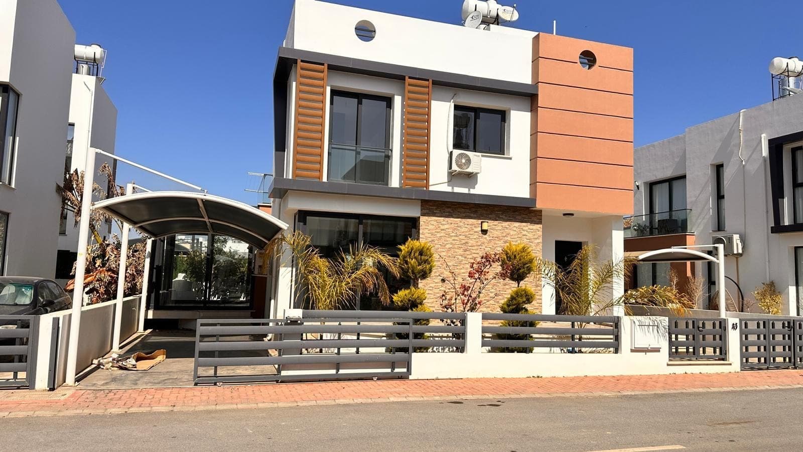 Exterior of a modern detached villa with garden and parking area.