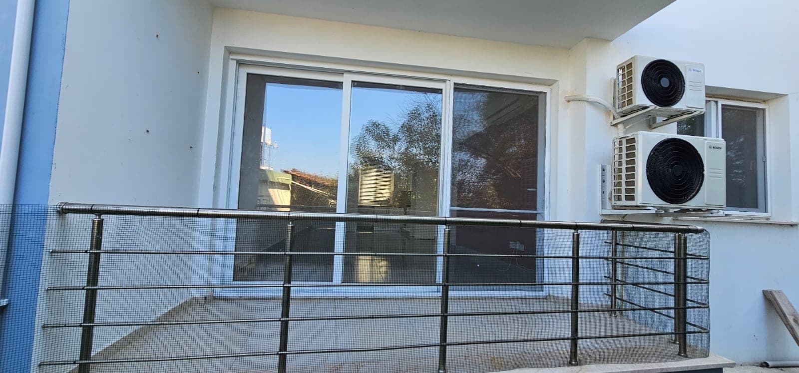 Balcony with metal railing and two air conditioning units on the exterior wall