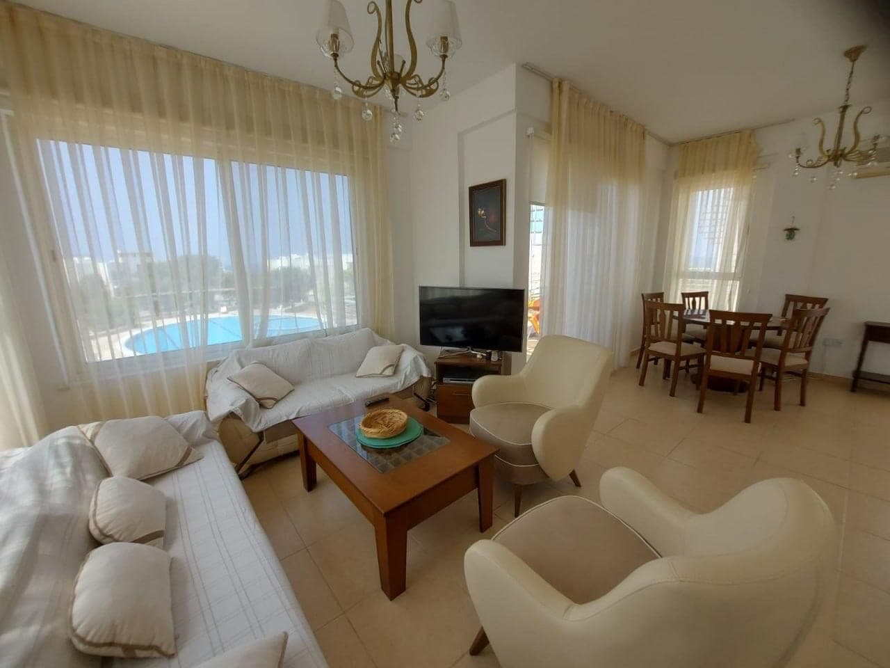 Spacious living and dining area, window with pool view.