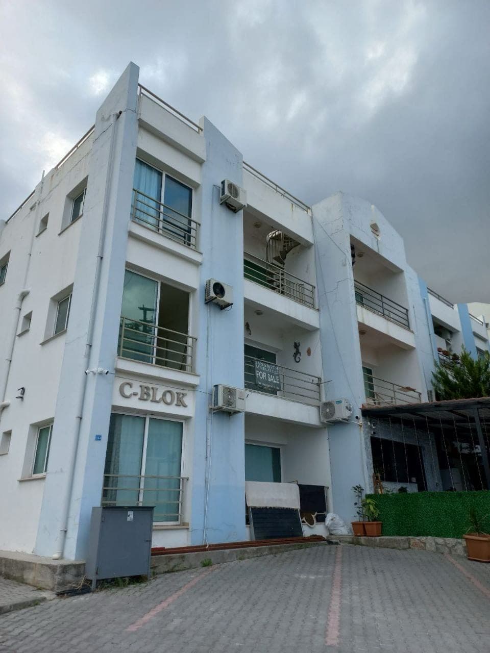 Exterior of the C-Blok apartment building with air conditioners and parking area.