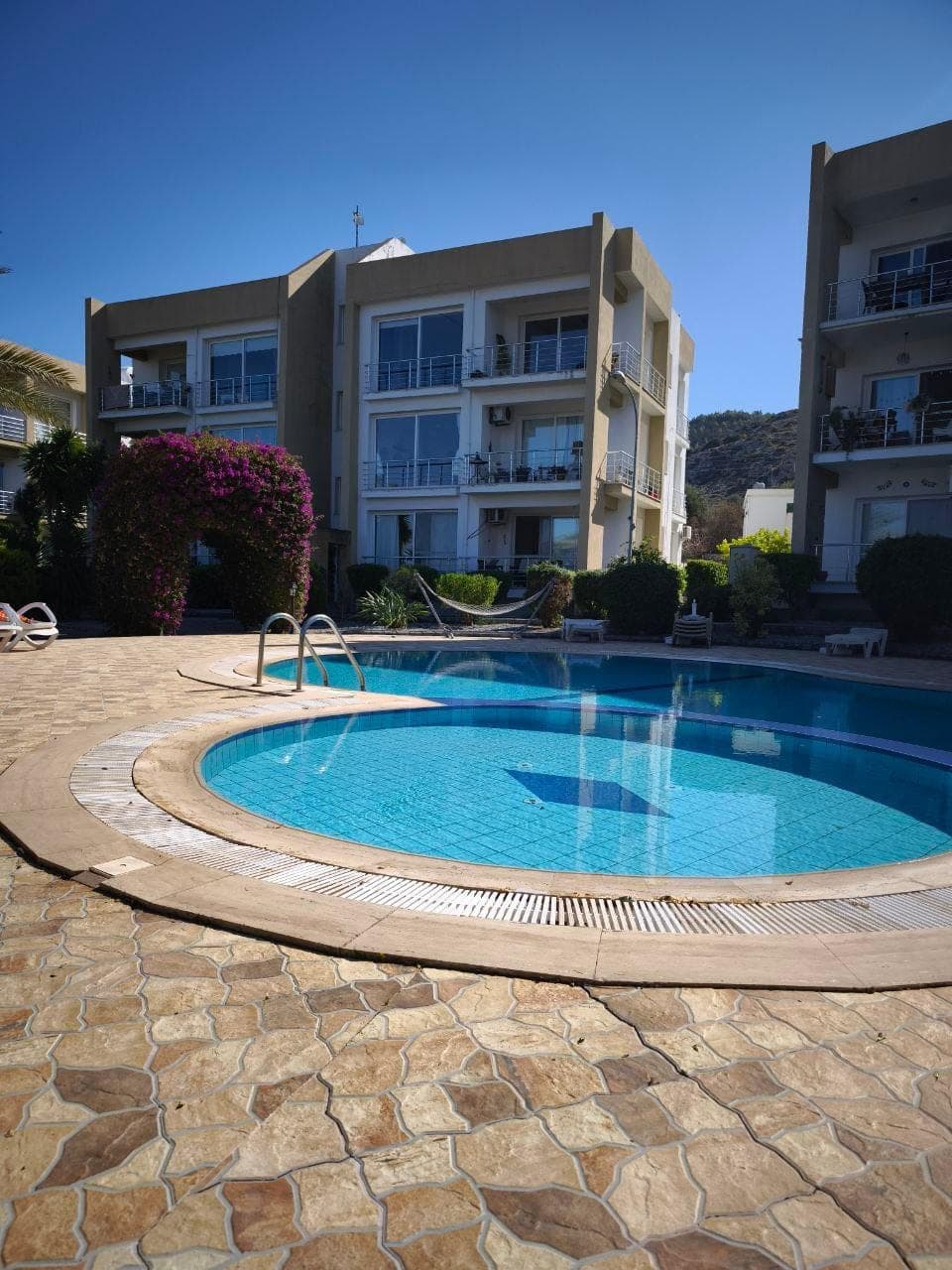 Shared pool and landscaped garden in front of the apartment building.