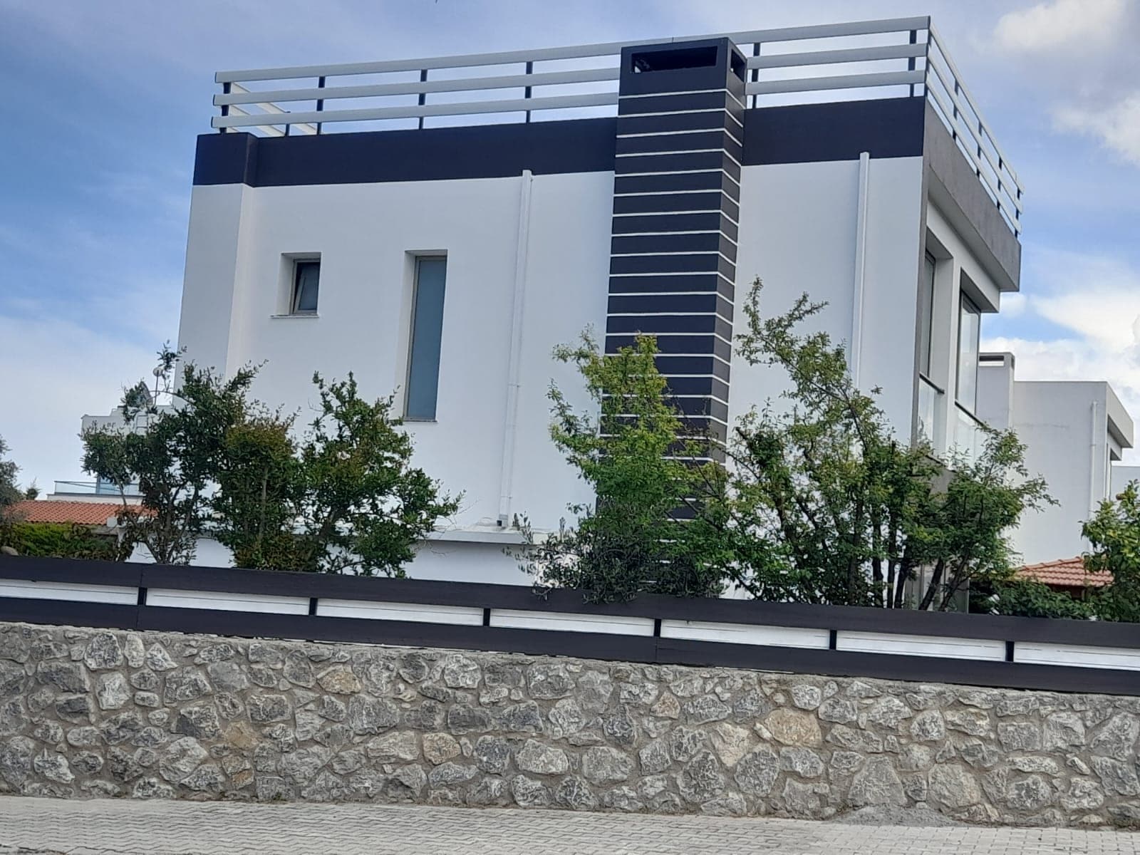 Beyaz ve koyu renk detaylı modern villa dış cephesi, taş duvar