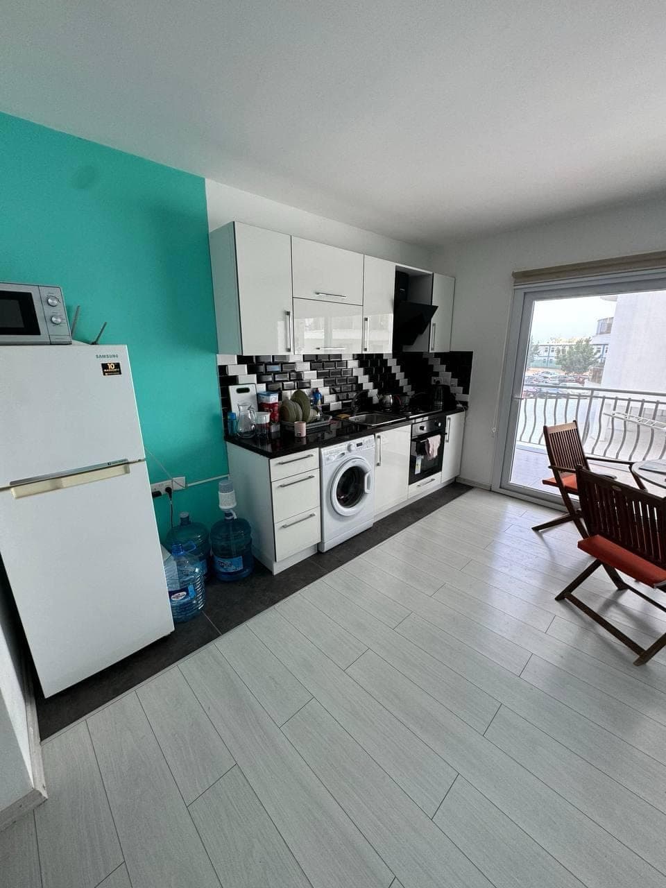 Kitchen with white cabinets, refrigerator, washing machine, and balcony door