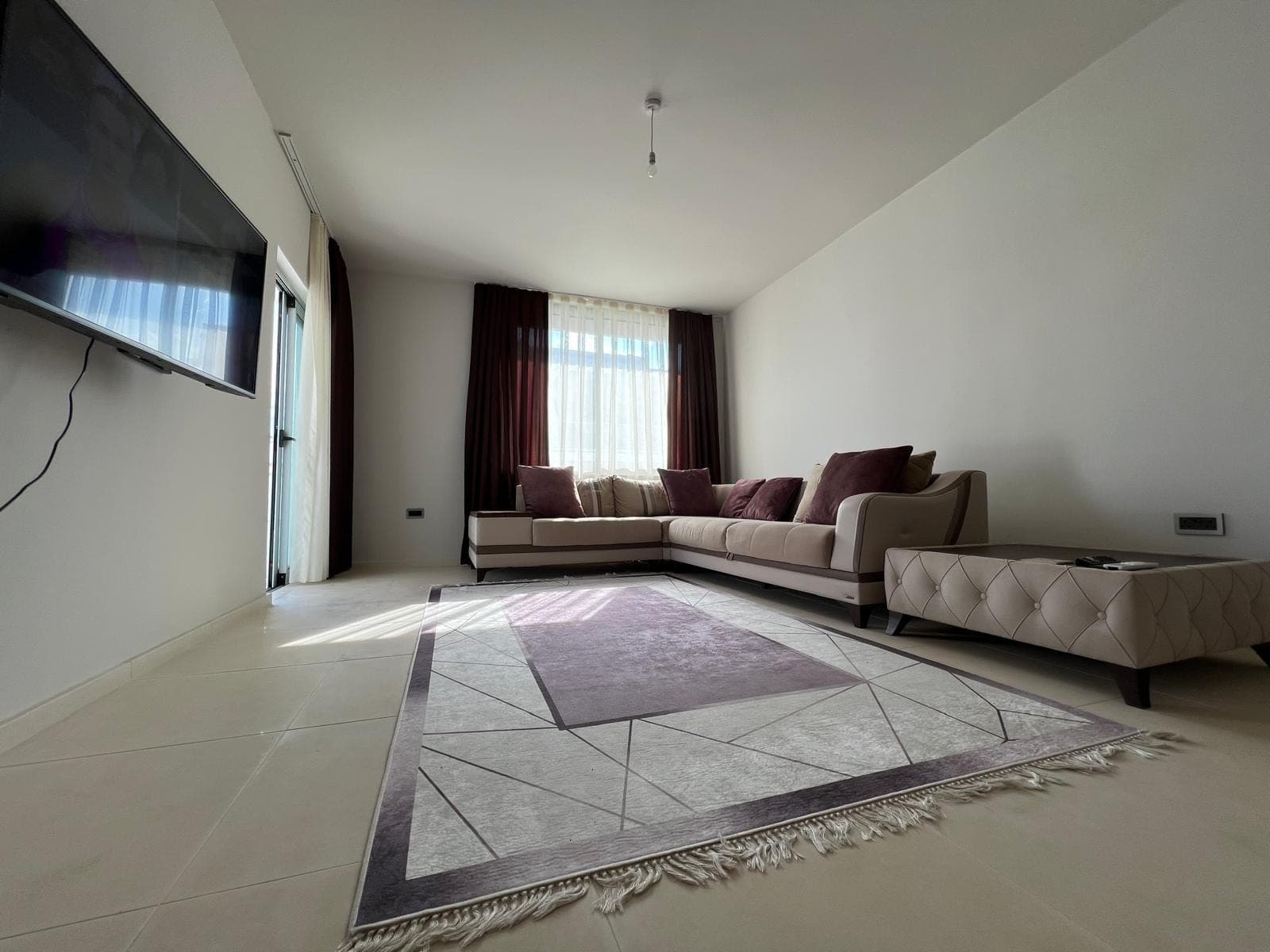 Spacious living room with corner sofa set and wall-mounted television